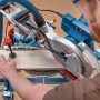 Bosch Professional GCM 305-254 Kapp- und Gehrungssäge beim Zuschnitt eines Holzbretts.