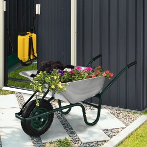 Juskys Schubkarre Garden 100L Silber mit Blumen und Erde vor Gartenhaus.