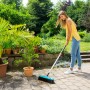Frau benutzt Gardena combisystem-Teleskopstiel zum Kehren einer Terrasse.
