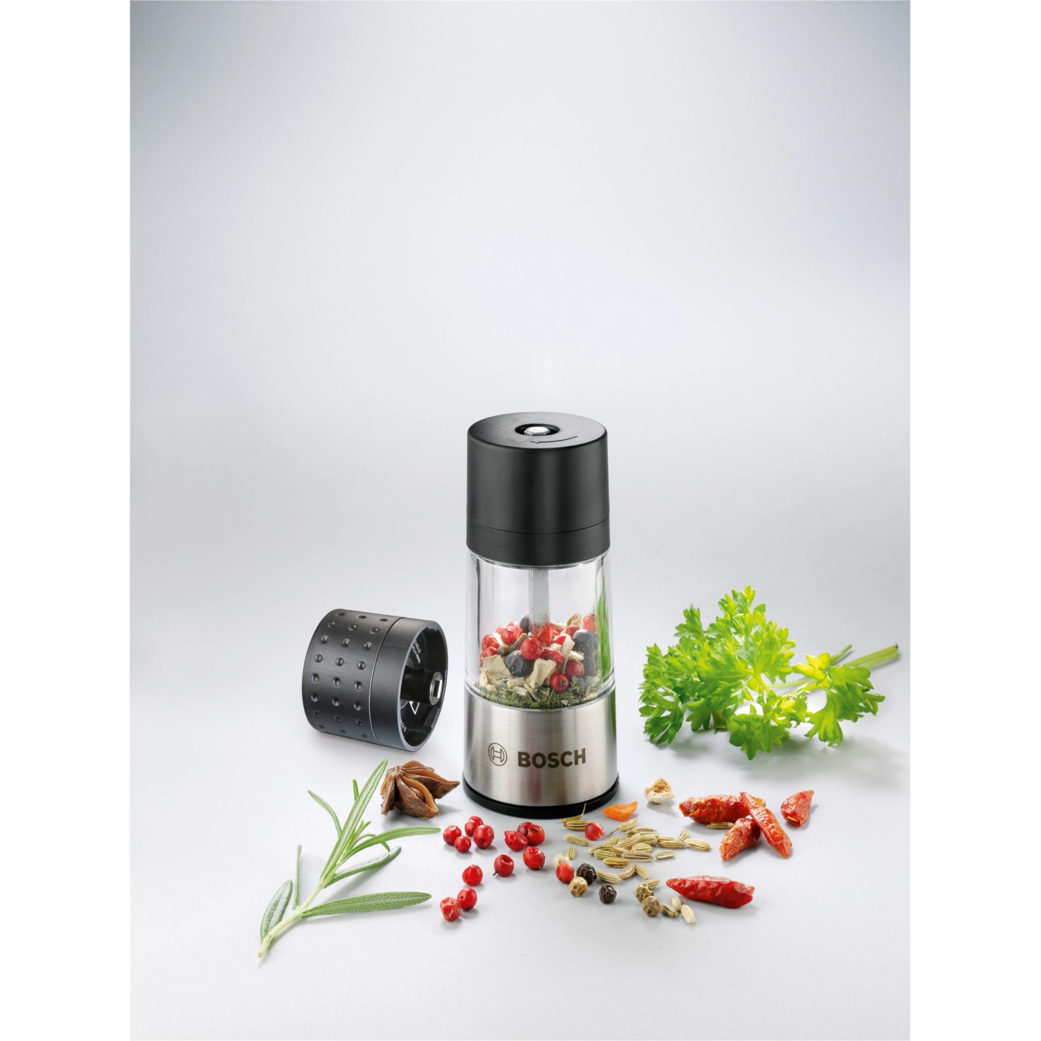 Bosch Ixo Gewürzmühlen-Aufsatz, transparent/schwarz, mit Gewürzen und Kräutern dekoriert.