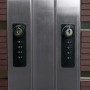 Zwei Zahlenschlösser mit Sicherheitscode an Mülltonnenbox aus Edelstahl und WPC Walnuss-Holzoptik.