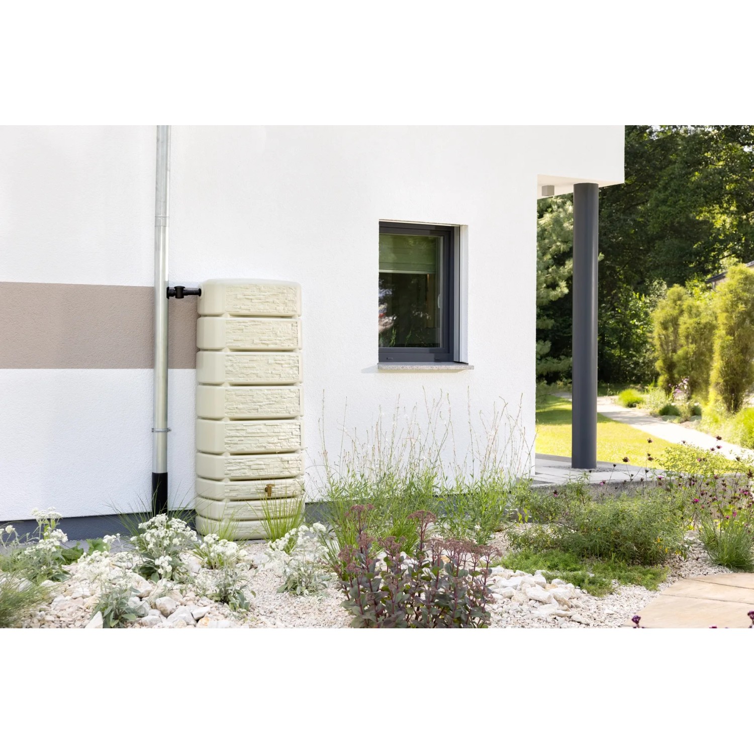 4rain Wandtank Slim Stone Decor 500 l, sandbeige, an Hauswand mit Regenrohr und Garten.