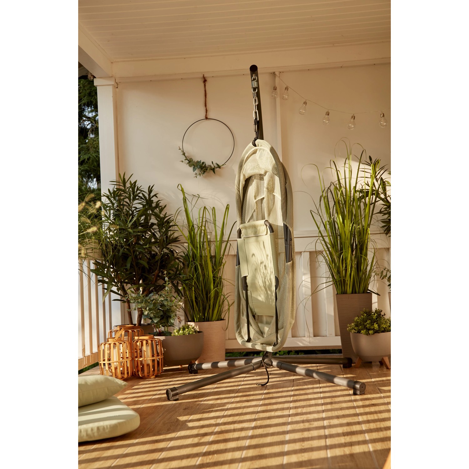 Zusammengeklappter Siena Garden Hängesessel Yobaya Light Green mit Stahlgestell auf einer Terrasse.