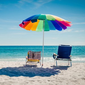 Strand-Szene mit buntem Sonnenschirm, zwei Liegestühlen und Meer.