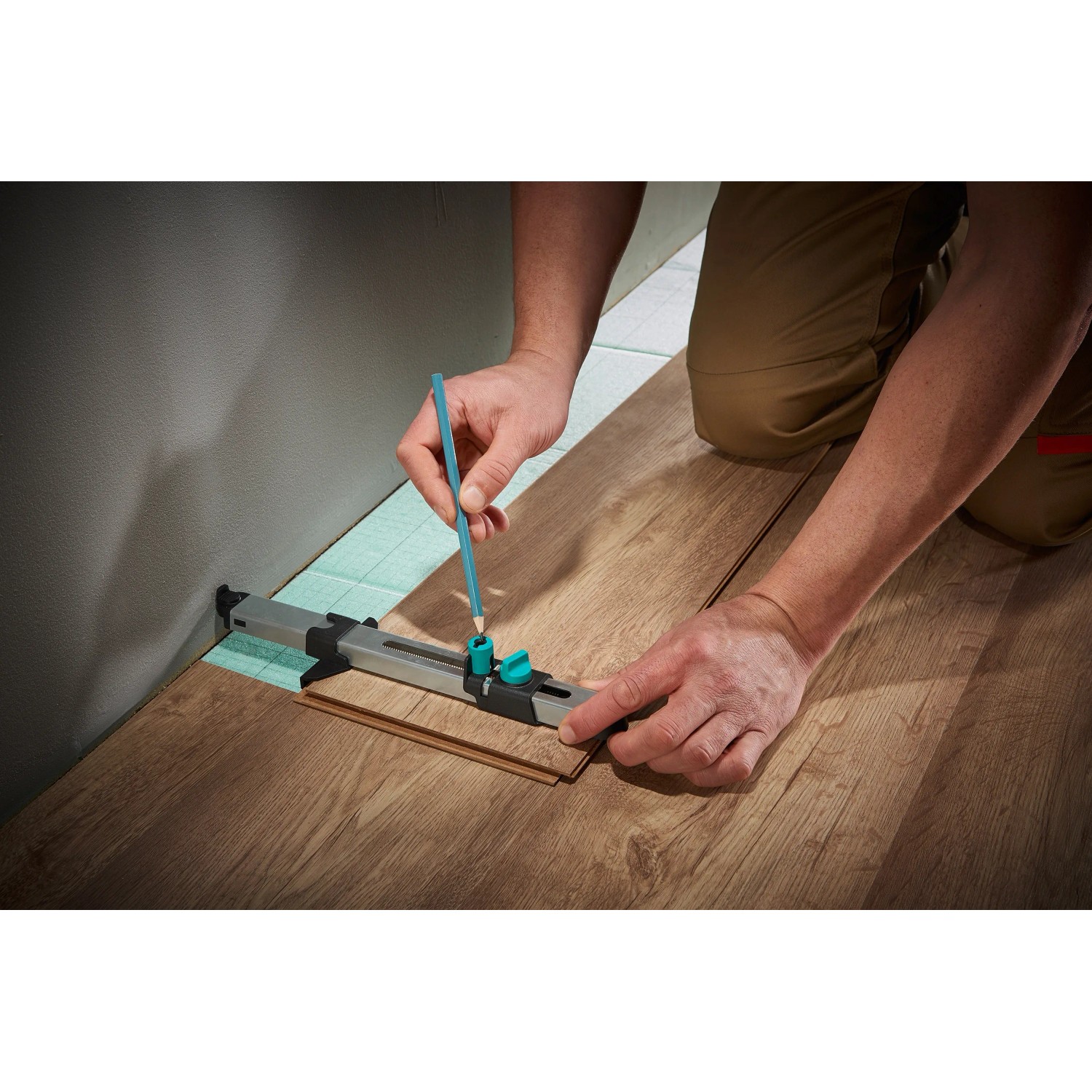 Wolfcraft Einpass-Set für Laminat: Handwerker zeichnet Laminat mit Einpasser an Wand an.