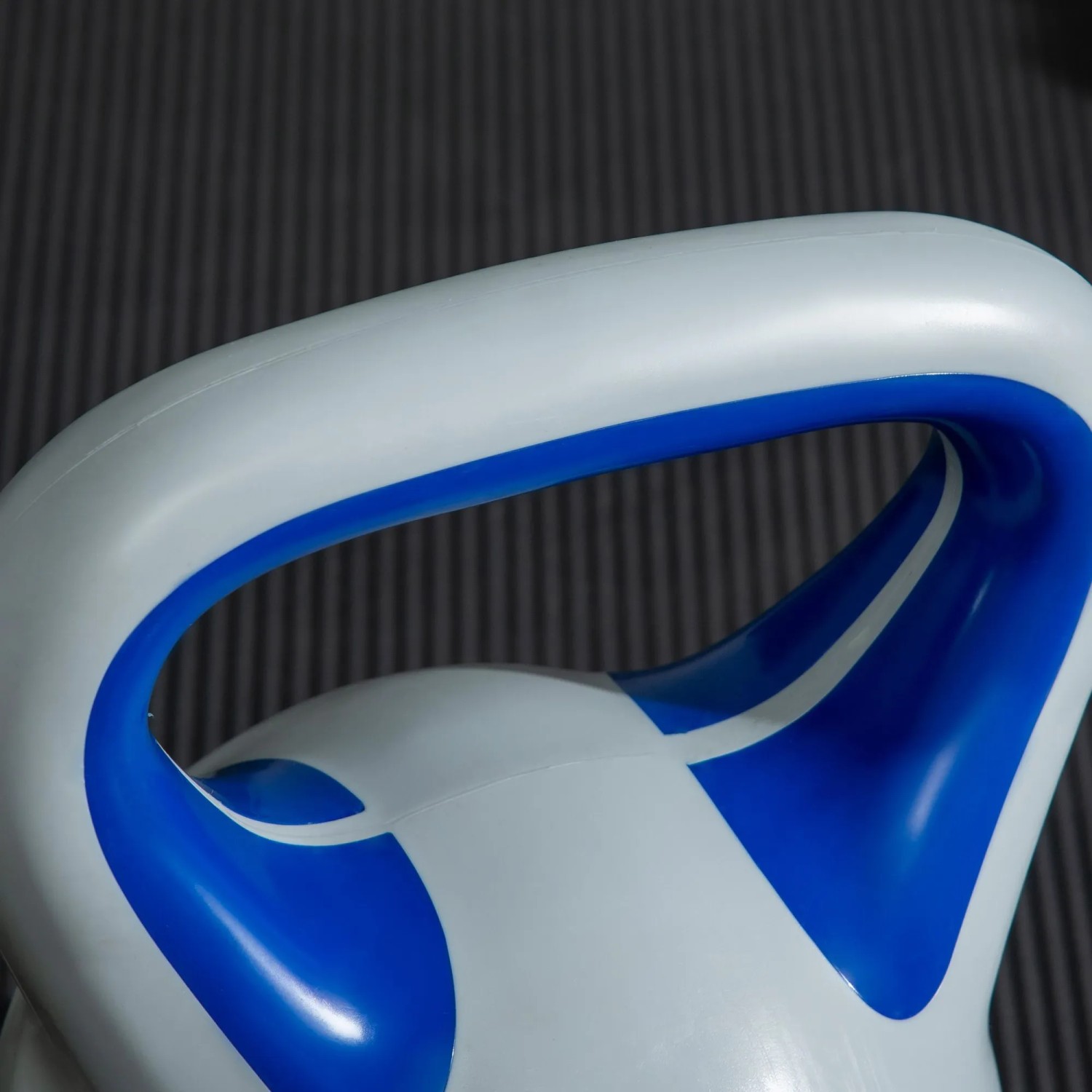 Nahaufnahme des breiten, weißen Griffs einer blauen SPORTNOW Kettlebell für Sport & Gewichtstraining.