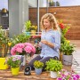 Frau installiert Gardena Solar-Bewässerung Aqua Bloom Set zwischen Pflanzen auf Balkon.