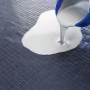 Knauf Kleber- und Boden-Elast wird aus einem blauen Eimer auf einen gefliesten Boden gegossen.