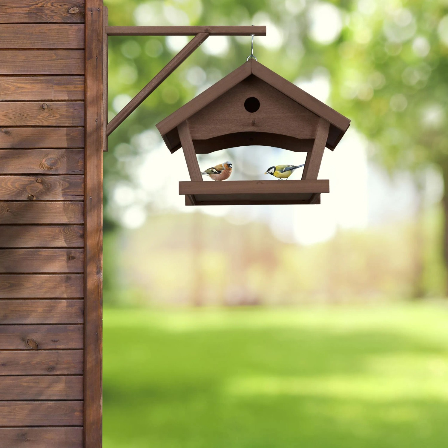 Dunkelbraunes Relaxdays Vogelfutterhaus aus Holz mit Stein, zur Wandmontage mit zwei Vögeln.