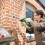 Mann bohrt mit dem Bosch Bohrhammer PBH 2500 SRE in eine Ziegelwand.