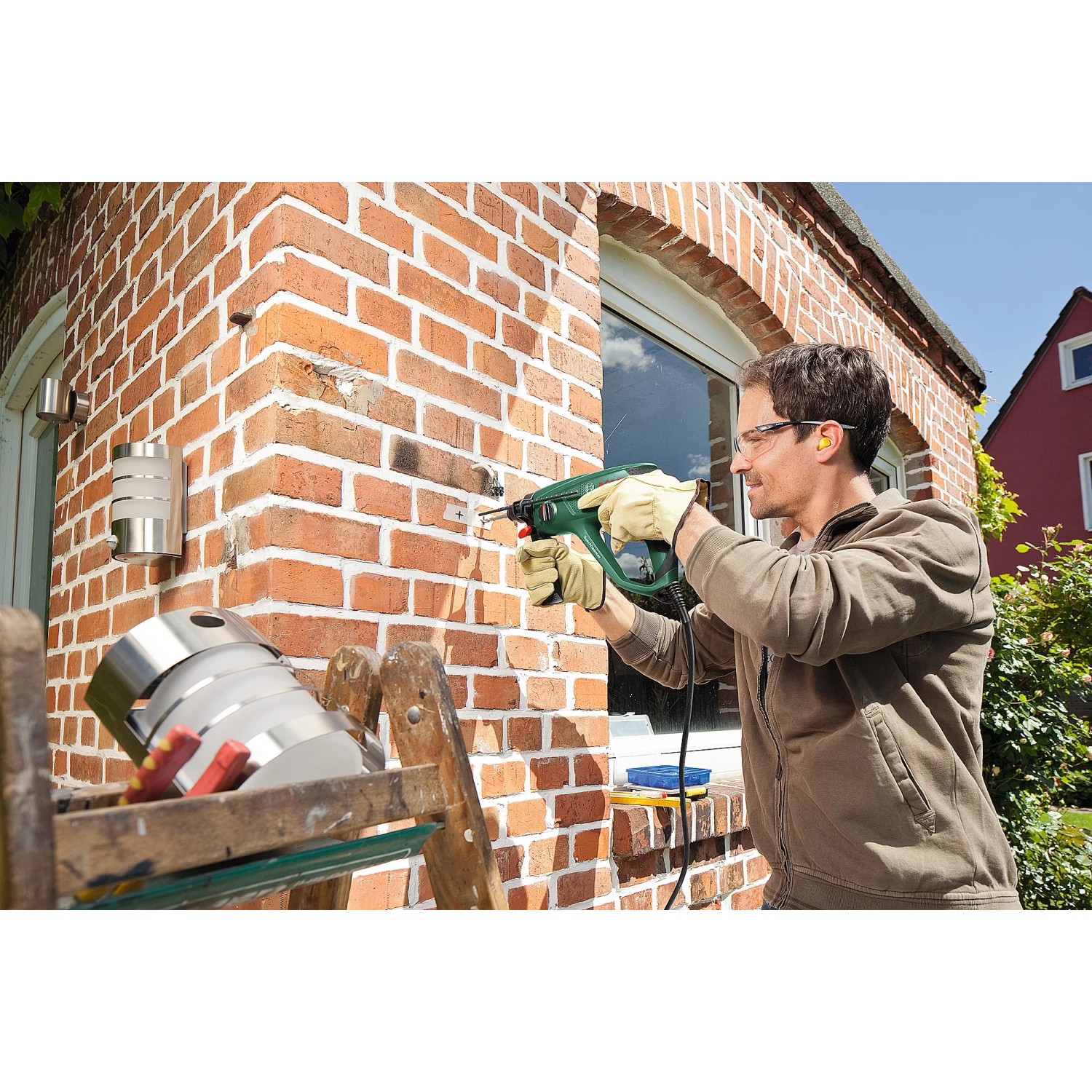 Mann bohrt mit dem Bosch Bohrhammer PBH 2500 SRE in eine Ziegelwand.