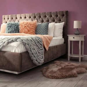 Modernes Schlafzimmer mit matter lila Wandfarbe, großem Bett, Nachttisch und Teppich. Tadessi Wall Select.