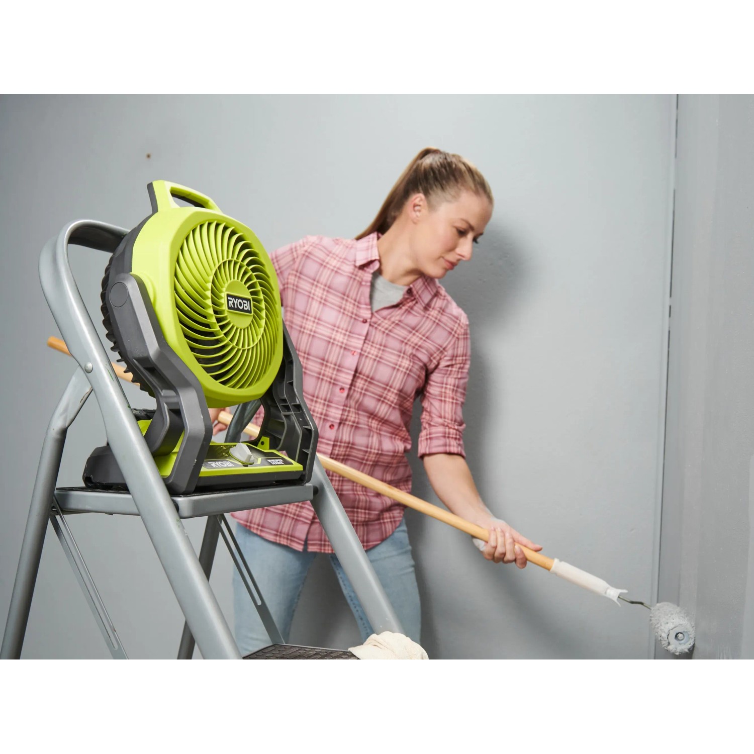 Ryobi Akku-Ventilator One+ RF18-0 auf Leiter, Frau streicht Wand. Akkugerät für flexible Kühlung.