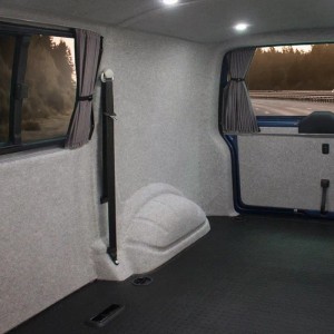 Innenraum eines Fahrzeugs mit grauer KARAT Nadelfilz Superflex Verkleidung an Wänden und Decke.