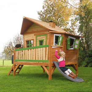 Axi Spielhaus Emma mit Rutsche, braun/grün, aus Holz mit Schornstein und schrägen Fenstern. Kinder spielen.