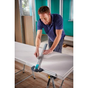 Mann schneidet Gipskartonplatte mit wolfcraft T-Schiene und Parallelschneider. Präzises Messwerkzeug.