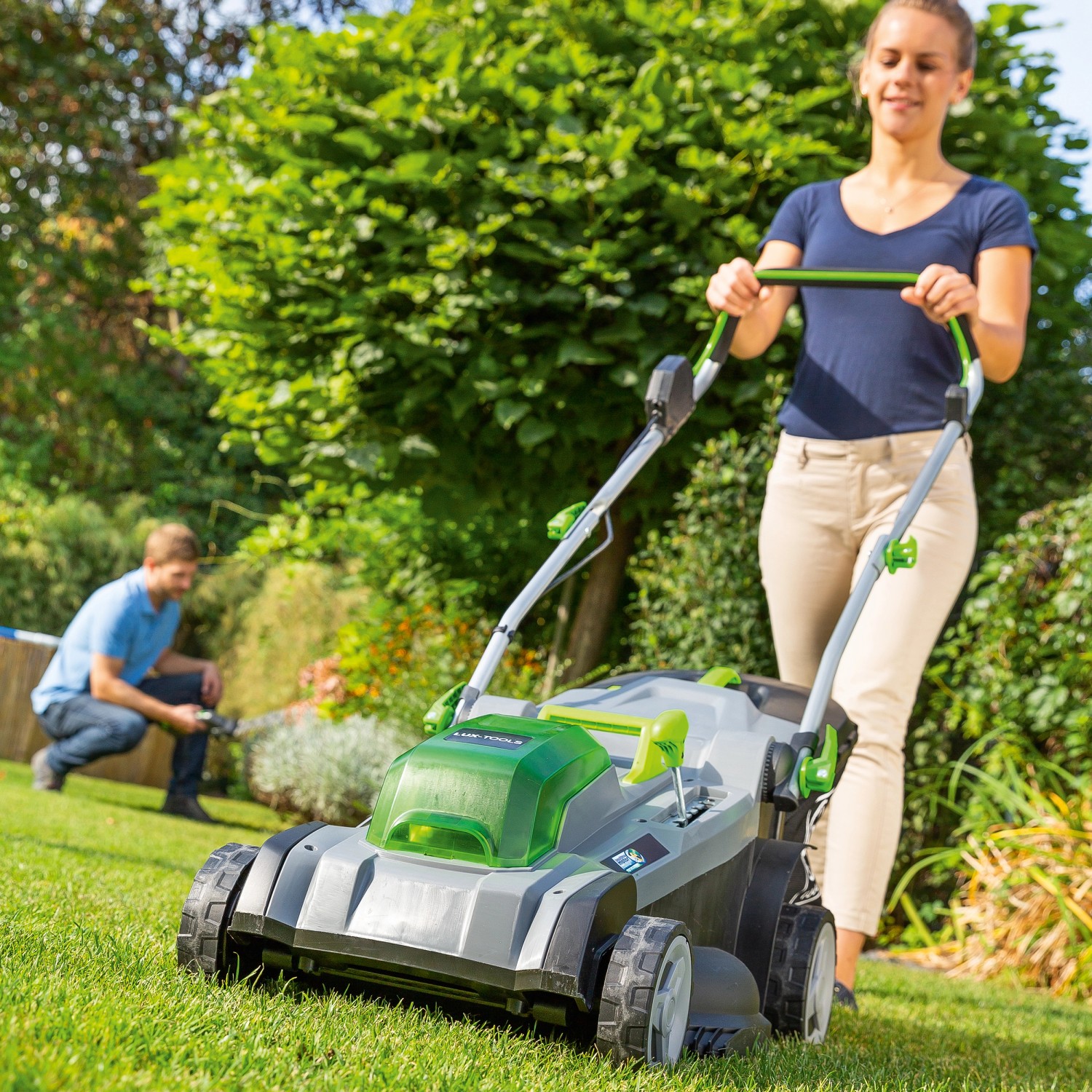 Frau bedient LUX Akku-Rasenmäher 40V im Garten. Inkl. 2 Akkus, ideal für bis zu 550 m² Rasen.
