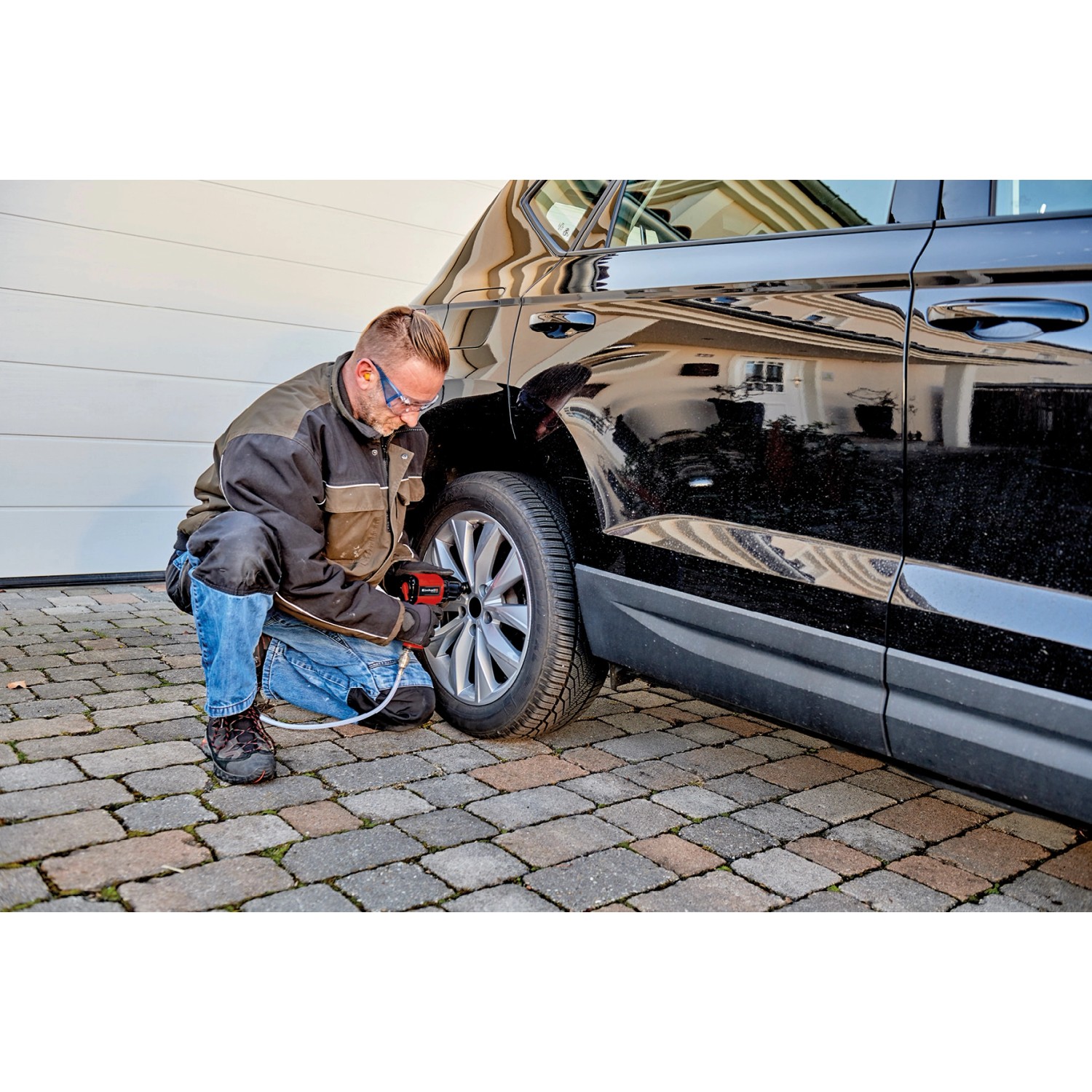Mann benutzt Einhell Druckluft-Set am Reifen eines Autos. Zubehör für Kompressoren.
