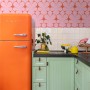 ESTAhome Retro-Tapete in Rosa/Rot mit Ornamenten in Küche mit orangem Kühlschrank.