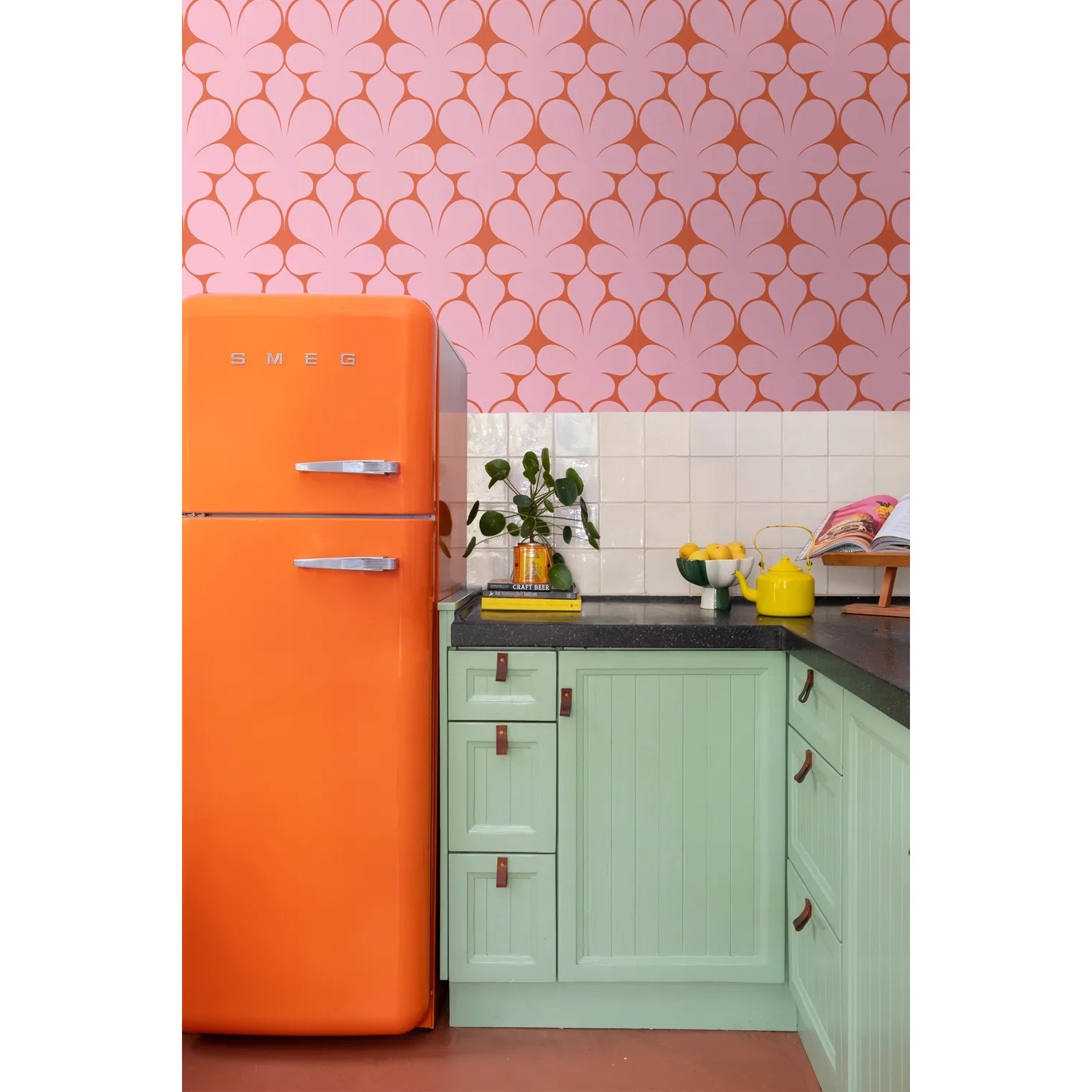 ESTAhome Retro-Tapete in Rosa/Rot mit Ornamenten in Küche mit orangem Kühlschrank.