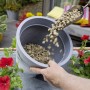 Westland Bims-Granulat wird in einen grauen Topf gefüllt. Drainage für Pflanzen.