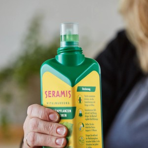 Grüne Seramis Vitalnahrung für Grünpflanzen und Palmen, 500ml Flasche in der Hand.