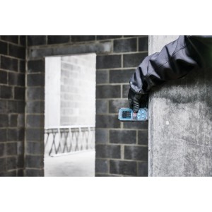 Behandschuhte Hand misst mit Bosch Laser-Entfernungsmesser GLM80-35C an Betonwand auf Baustelle. Präzises Messwerkzeug.