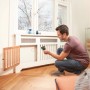 Mann misst mit Bosch AdvancedTemp Infrarot-Thermometer Temperatur an Heizkörper.