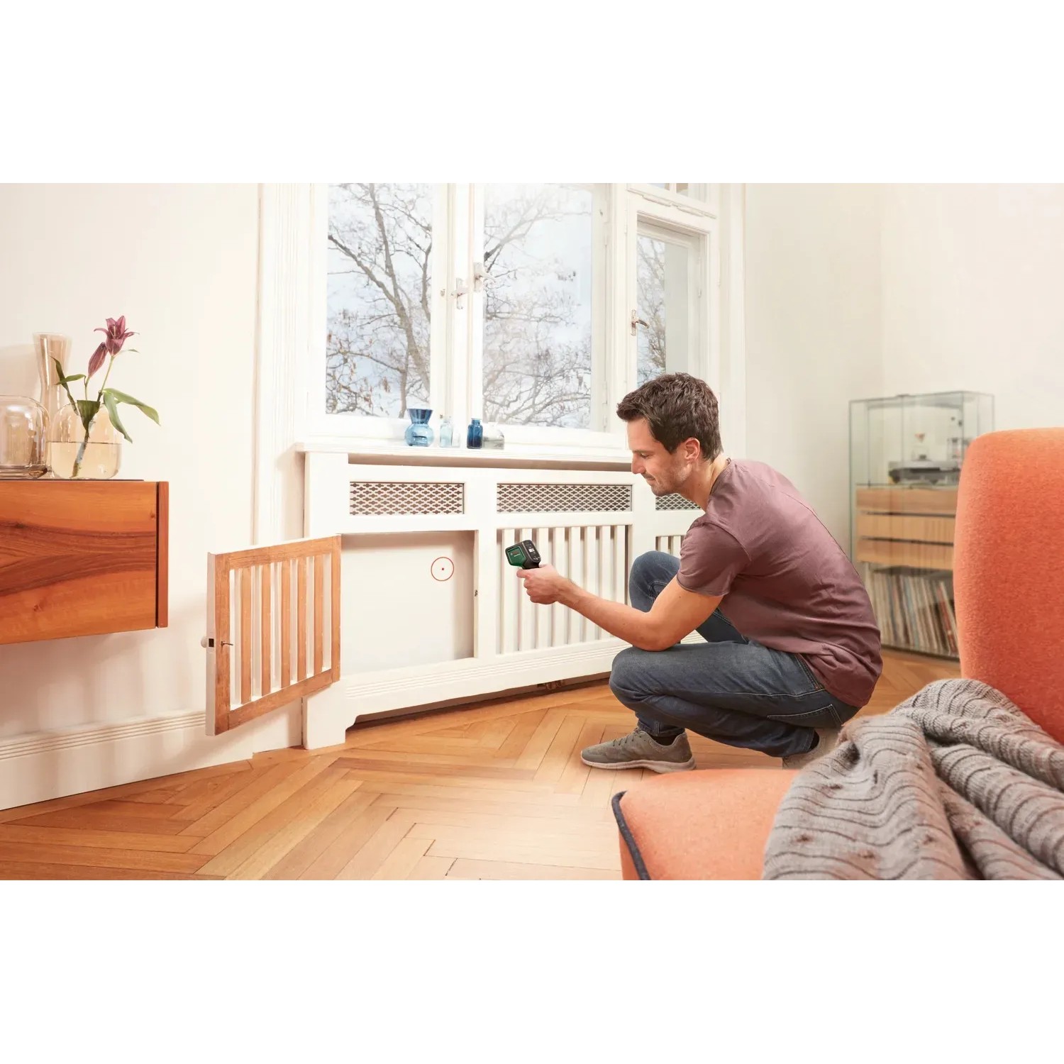 Mann misst mit Bosch AdvancedTemp Infrarot-Thermometer Temperatur an Heizkörper.