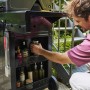Schwarzer Char-Broil Gasgrill Essential 3 G mit Mann, der Gewürze im Stauraum verstaut.