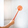 Orange Windhager Fliegenklatsche beim Einsatz gegen eine Fliege an der Wand.