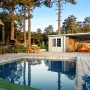 Hellbraunes Palmako Ella Holz-Gartenhaus mit Flachdach und Anbau am Pool.