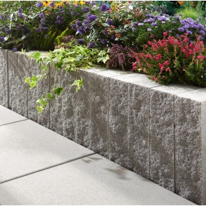 Montania Mauerstein Silbergrau als Beetbegrenzung mit Bepflanzung im Garten.