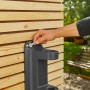 Montage der Gardena Wand-Schlauchbox XL an einer Holzwand mit Schraubenschlüssel.