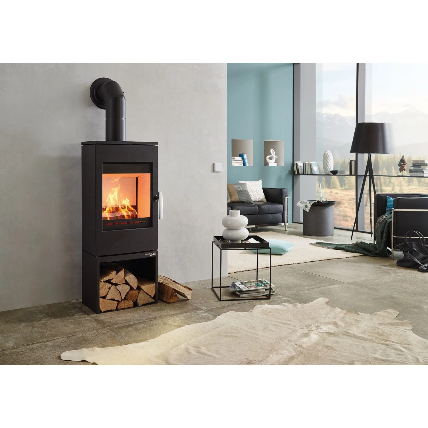Schwarzer Haas+Sohn Kaminofen mit Holzfach und brennendem Feuer im Wohnraum.