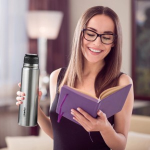 Frau mit Relaxdays Edelstahl Trinkflasche (500ml, silber/schwarz) und Buch. Ideal für Camping.