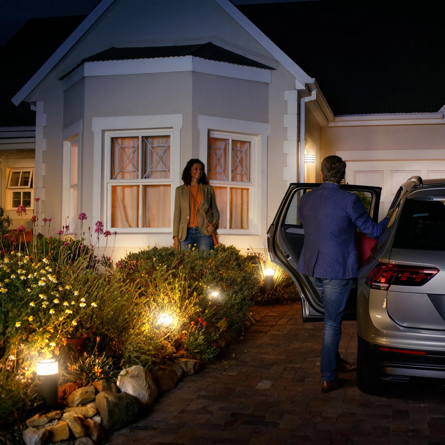 Philips Hue Calla Sockelleuchte im Garten, warmweißes Licht beleuchtet Weg und Pflanzen.