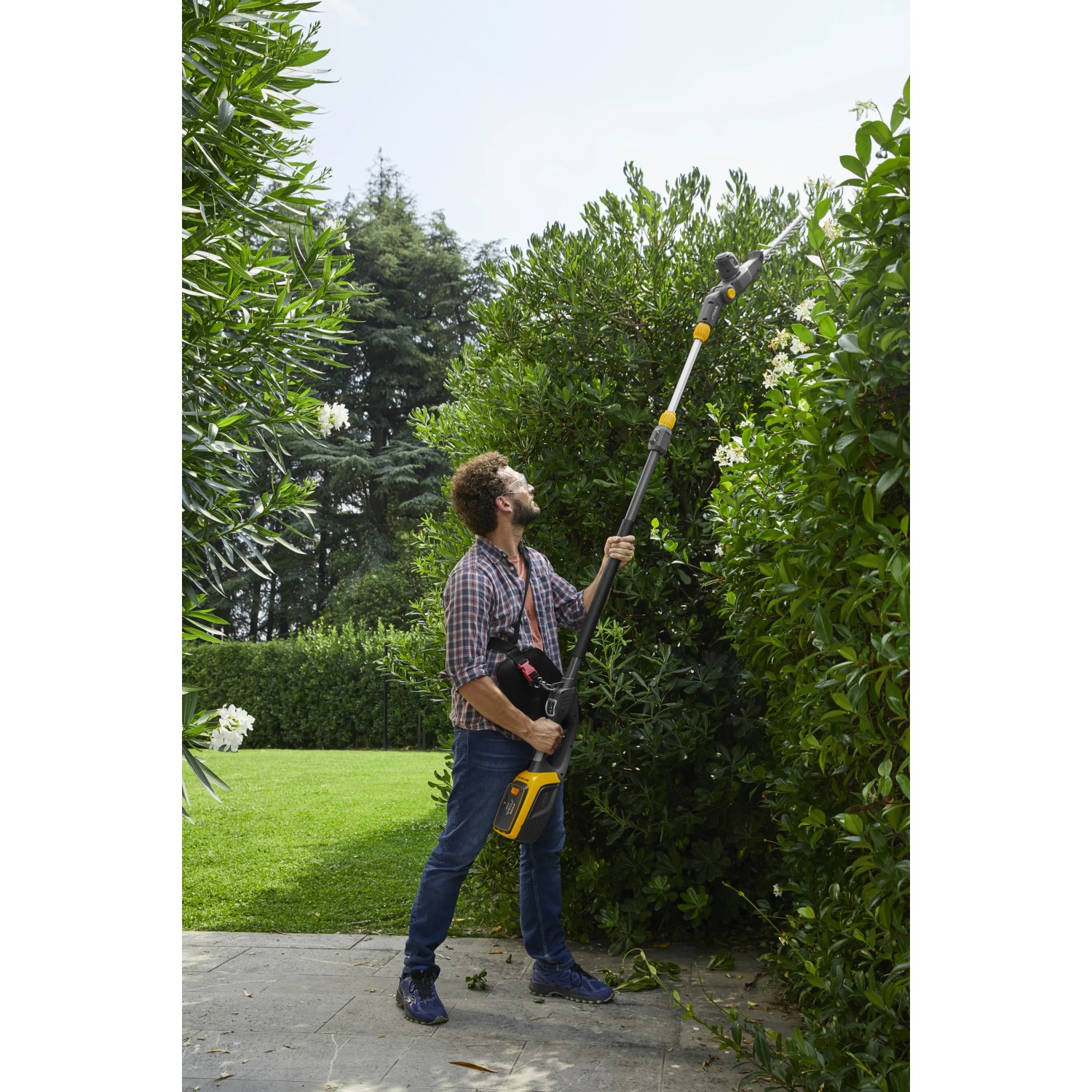 Mann schneidet Hecke mit Stiga Akku-Multitool MT 500e Akku-Heckenschere.