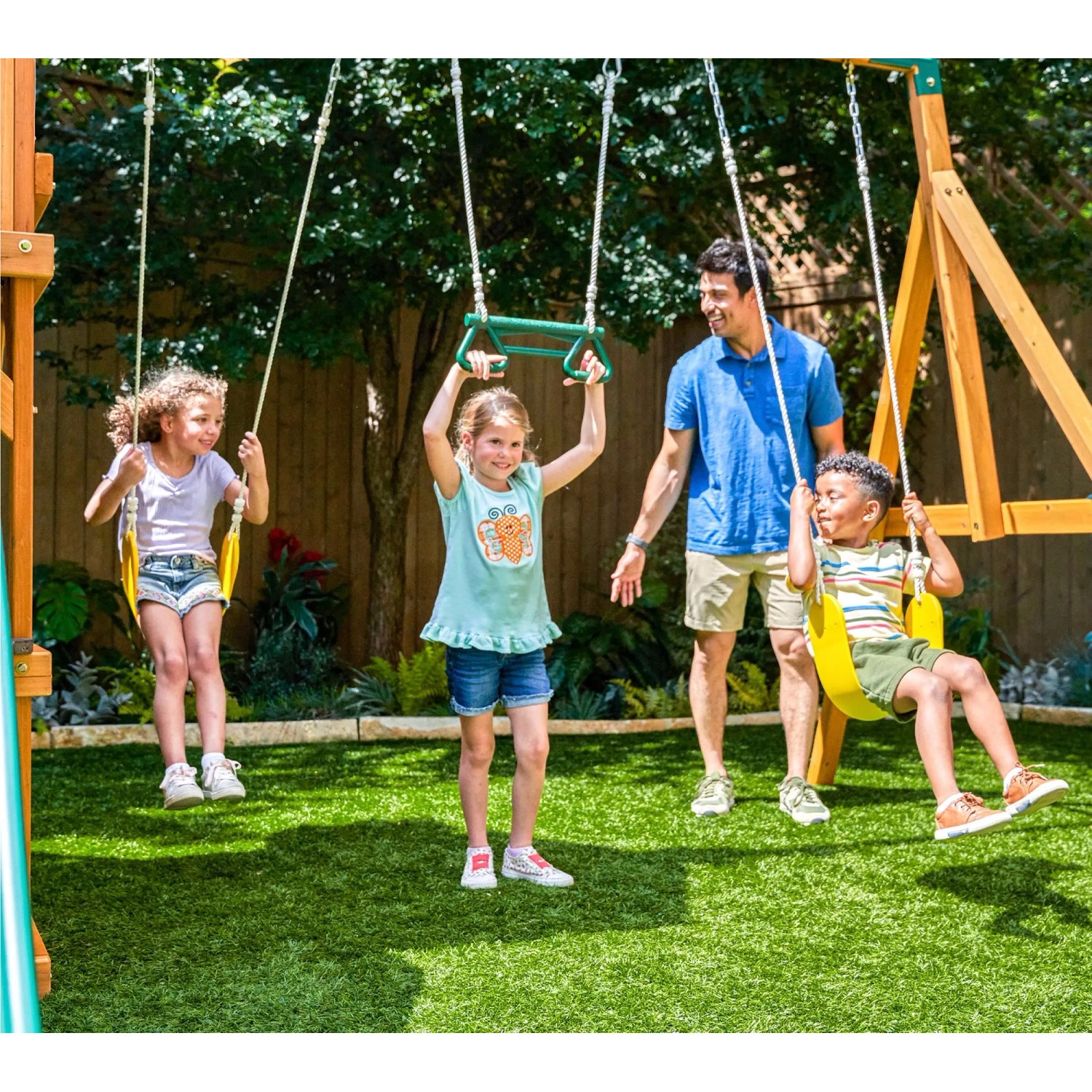 Zwerkules Spielturm Bolzo mit Kindern auf Schaukeln und Reckstange im Garten.