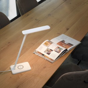 Weiße LED-Tischleuchte Florentina von Just Light mit Ladefunktion auf einem Holztisch.