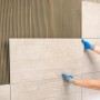 Verlegen von hellen Naturstein-Fliesen mit Knauf Flexkleber. Fliesenkleber auf der Wand.