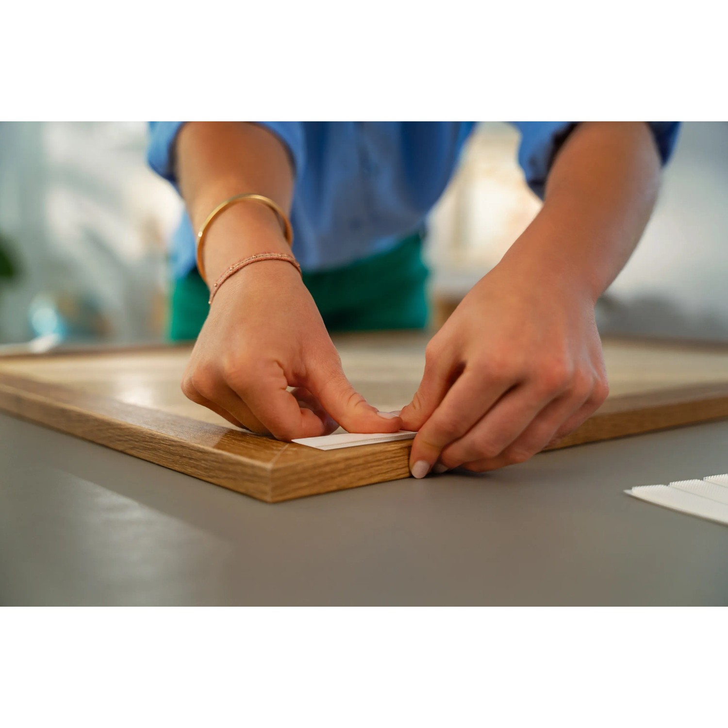 Anbringen von Tesa Powerstrips Click-Small an einem Bilderrahmen. Klebenägel für sichere Befestigung.