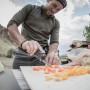 Mann schneidet Gemüse mit dem Gerber Multi-Tool Truss. Vielseitiges Werkzeug für Camping und Outdoor.