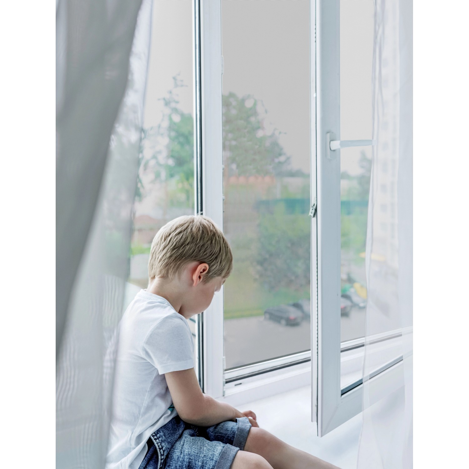 Weißes Avosdim Insektenschutzrollo aus Aluminium am Fenster, Kind sitzt davor.