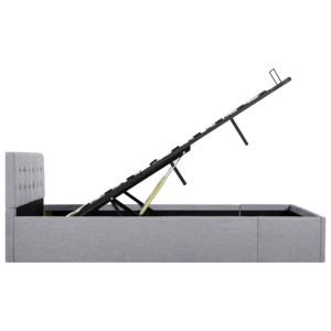 Hellgraues Stauraumbett (120x200 cm) mit hochgeklapptem Lattenrost und Stauraum unter der Liegefläche.