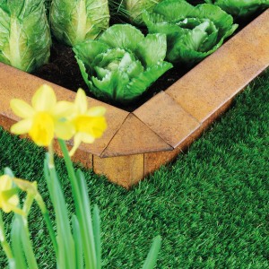 Bellissa Schneckenblech Corten Eckteil als Beeteinfassung mit Salat und Narzissen im Garten.