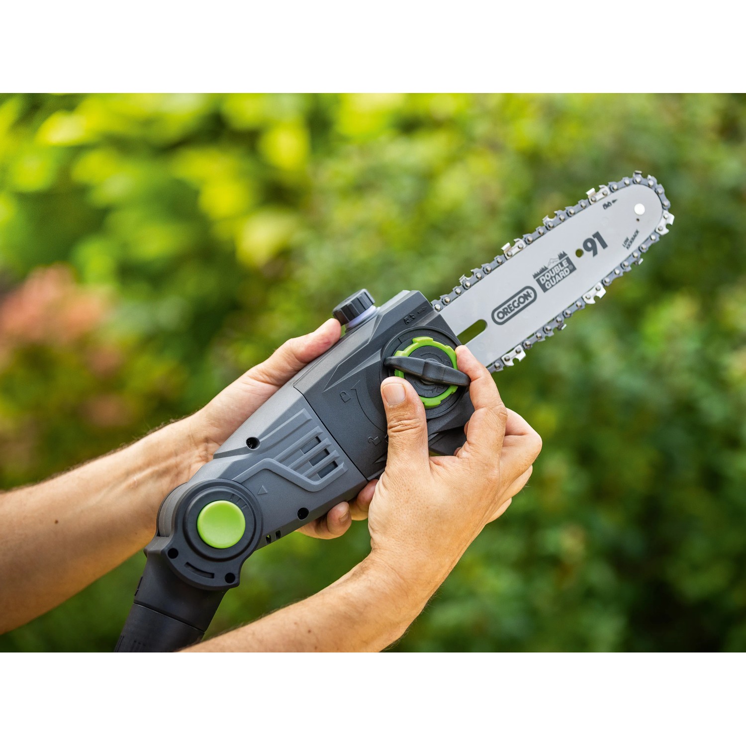 LUX-TOOLS Akku-Teleskop-Astsäge: Detailaufnahme der Kettensäge mit Händen vor grünem Hintergrund.