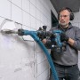 Mann arbeitet mit Bosch Professional Akku-Schlaghammer GSH 18V-5 an einer Wand.