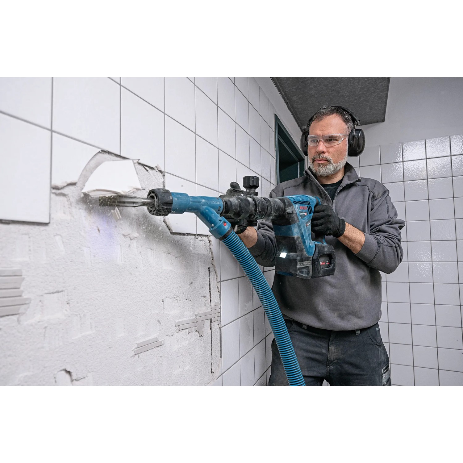 Mann arbeitet mit Bosch Professional Akku-Schlaghammer GSH 18V-5 an einer Wand.