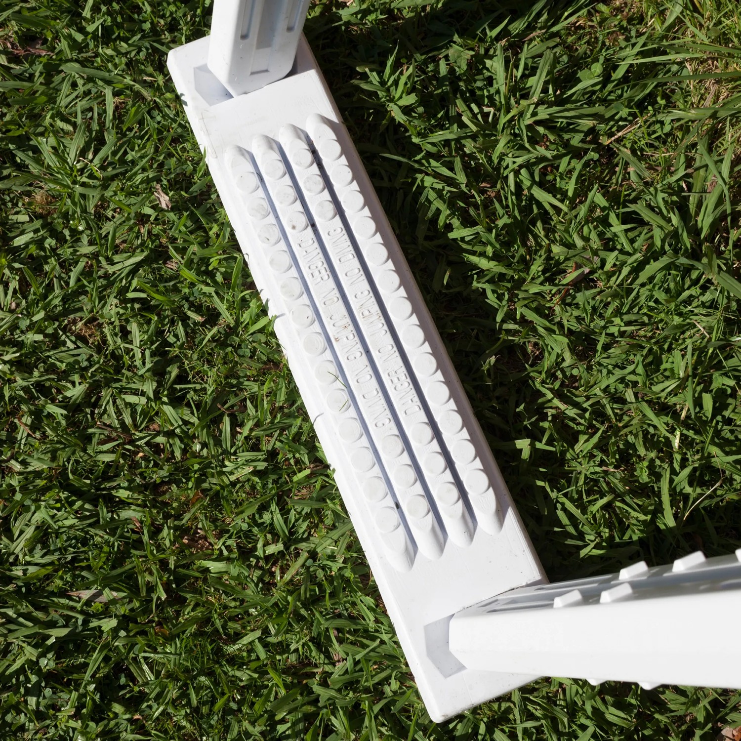 Detailaufnahme der rutschfesten Stufe einer weißen Gre Sicherheitsleiter aus HDPE für Pools.